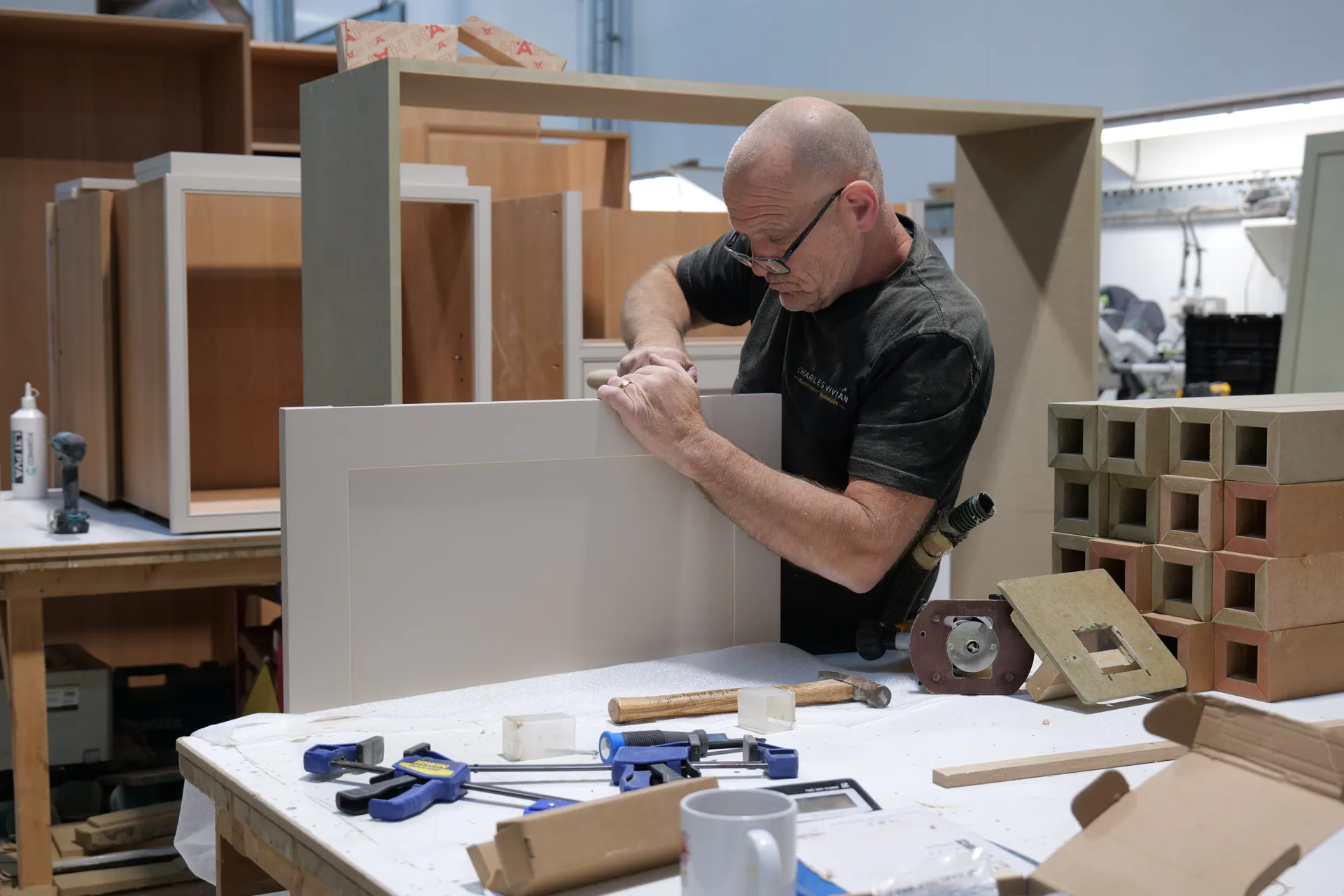A Charles Vivian craftsman assembling cabinetry at the workshop bench