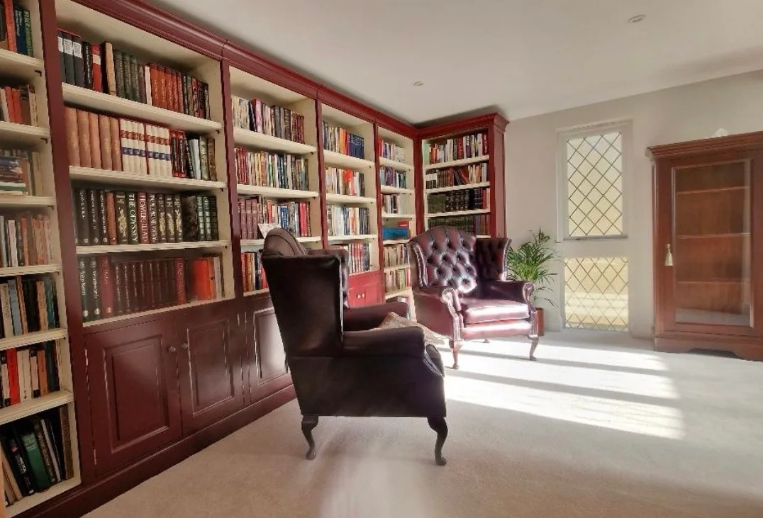 Floor-to-ceiling library bookcases with cupboards below, by Charles Vivian