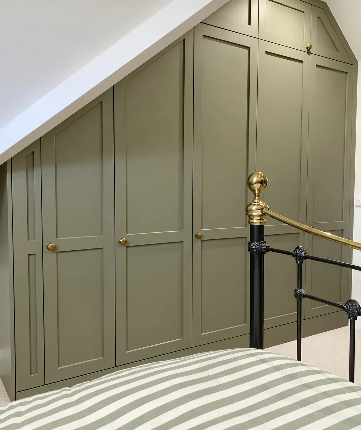 Sage-green wardrobes built into the eaves, Cambridge