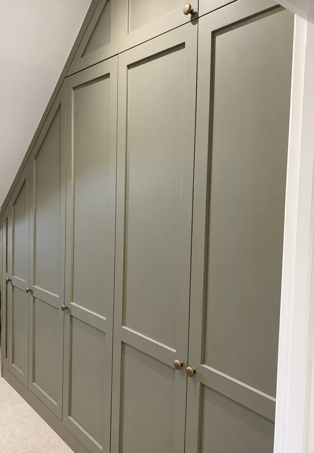 Sage-green wardrobes built into the eaves, Cambridge